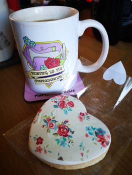 Iced shortbread biscuit with a mug of tea with a picture of a sewing machine saying sewing is my superpower placed on a coffee table